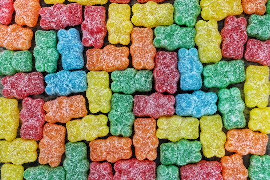 Colorful trays of gummies arranged in neat rows on a factory table.