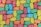A colorful assortment of gummy bear candies arranged closely together in a uniform pattern. The candies are covered in a light dusting of sugar.