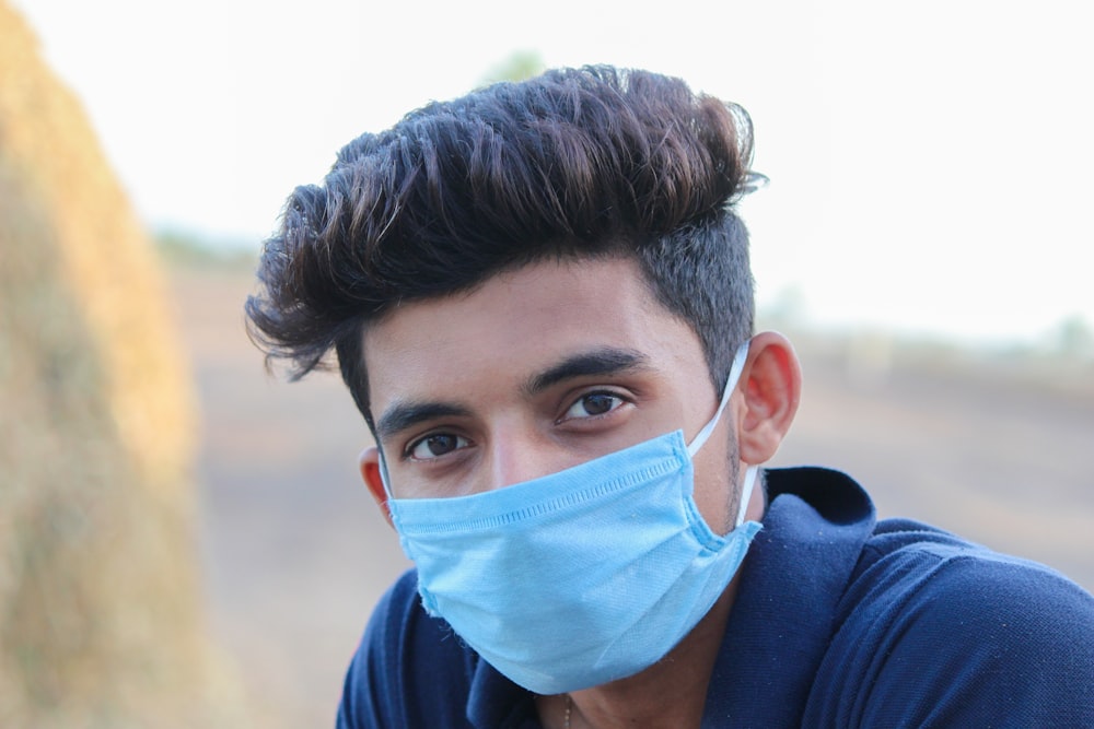 man in blue shirt wearing white face mask