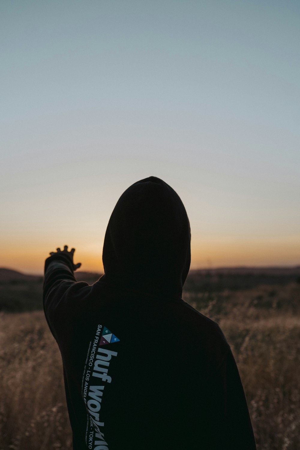 person in black hoodie standing on brown grass field during daytime