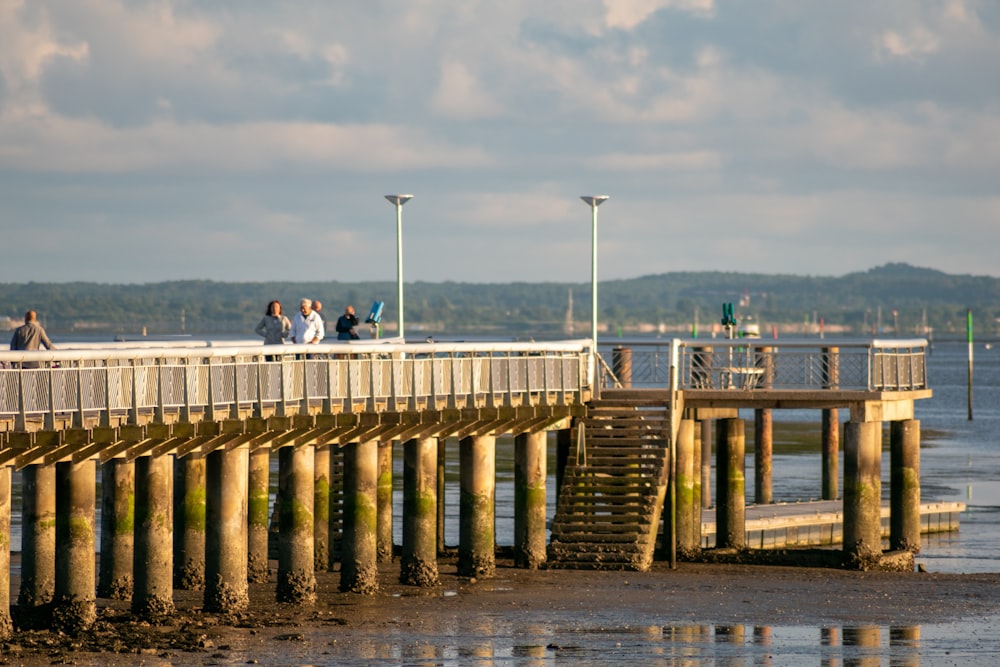 man in black jacket and blue denim jeans standing on brown wooden dock during daytime