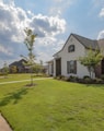 white and brown house near green grass field under white clouds and blue sky during daytime