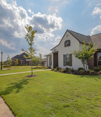 white and brown house near green grass field under white clouds and blue sky during daytime