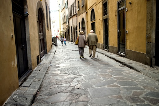people walking on sidewalk between buildings during daytime in Siena Italy