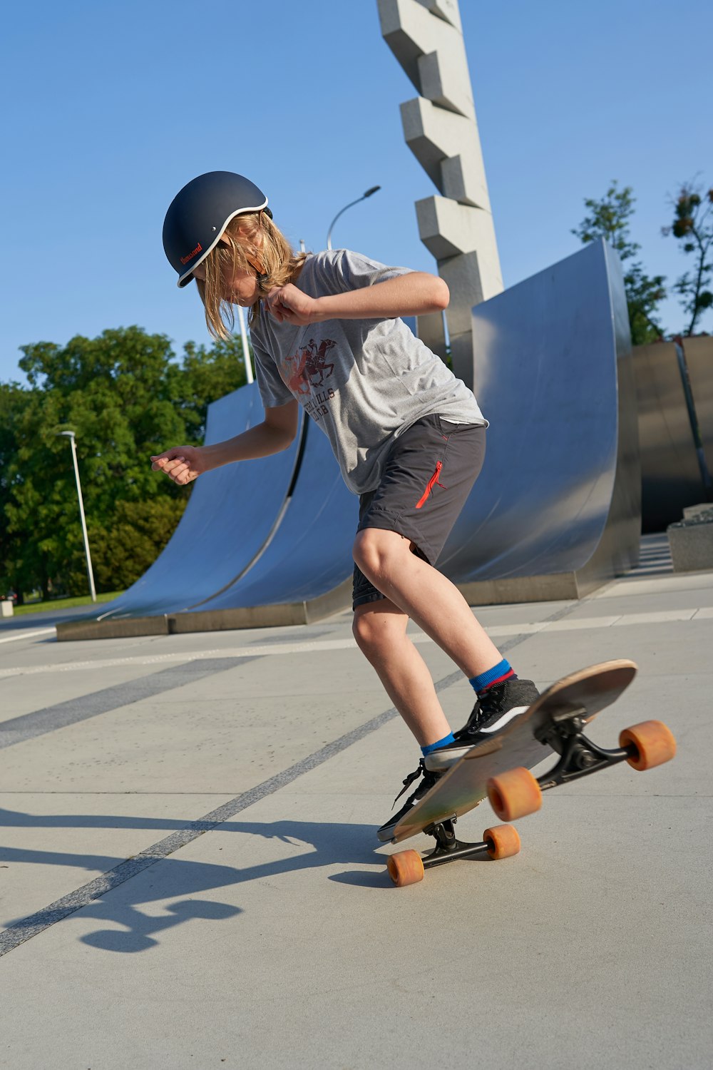 man in grey t-shirt and black shorts riding skateboard during daytime