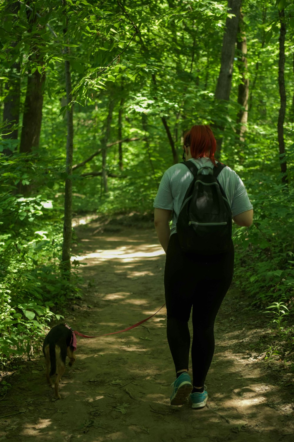 woman in gray t-shirt and black pants standing on forest during daytime