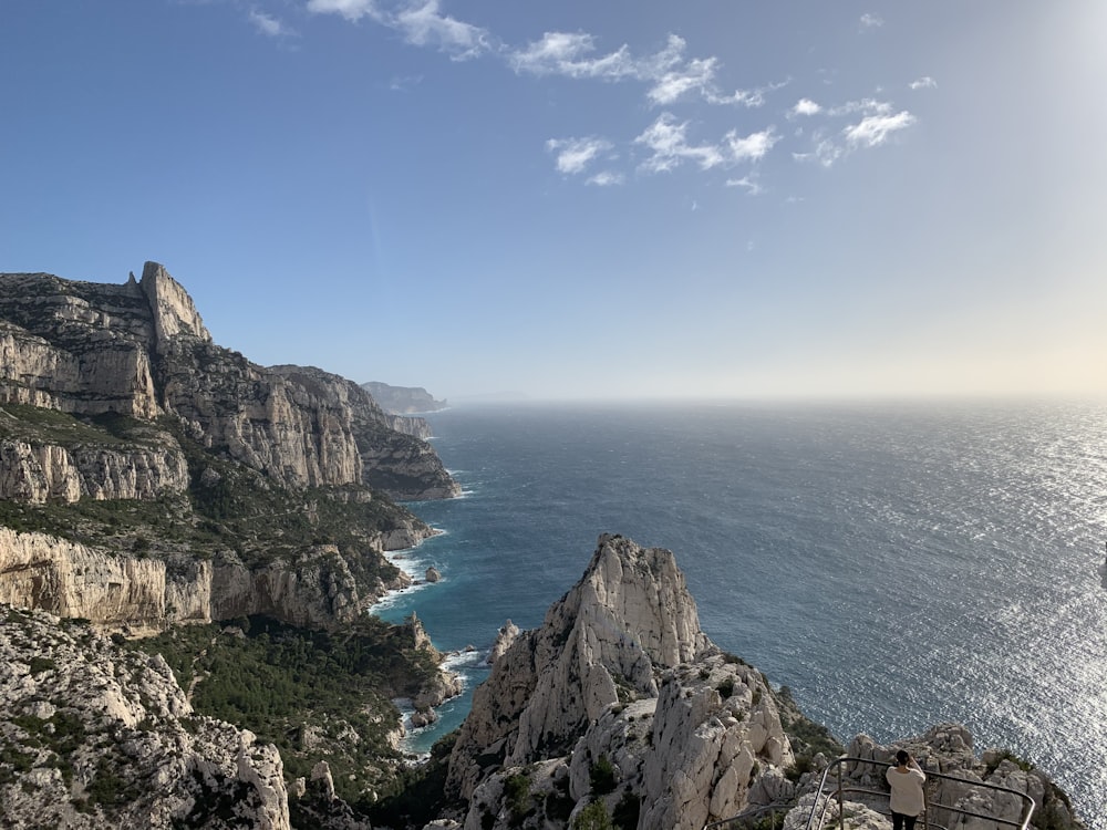 brown rocky mountain beside blue sea under blue sky during daytime