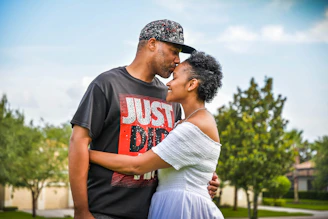 man in black crew neck t-shirt kissing woman in white dress