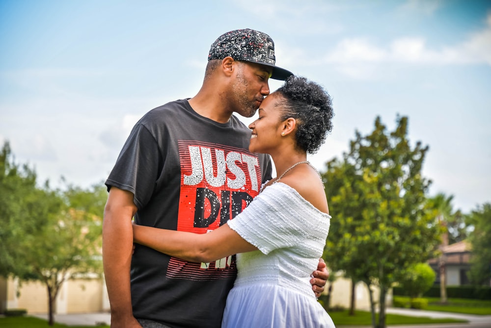 homem na t-shirt preta do pescoço da tripulação beijando a mulher no vestido branco