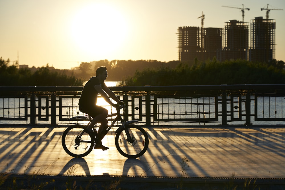 man riding bicycle on bridge during daytime
