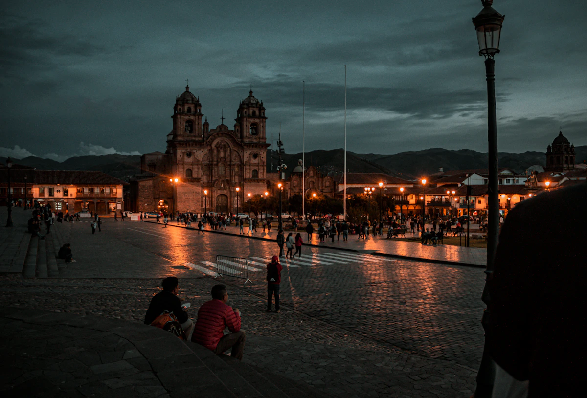 People walking through illuminated historic streets in Cusco at night