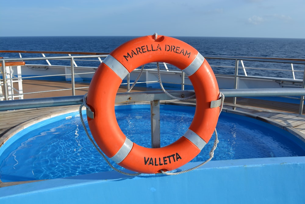 Boya salvavidas naranja y blanca en la piscina durante el día