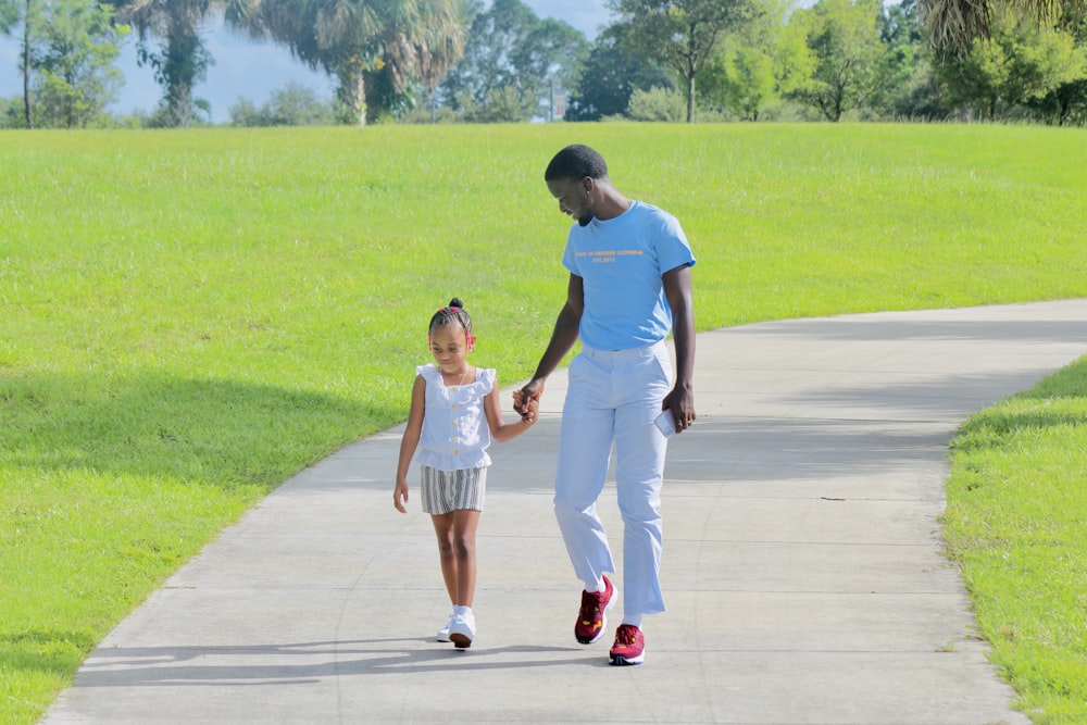 man and woman holding hands while walking on sidewalk during daytime