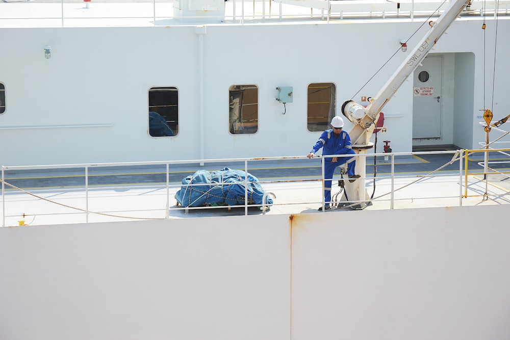 woman in pink shirt and blue denim jeans standing on white ship during daytime