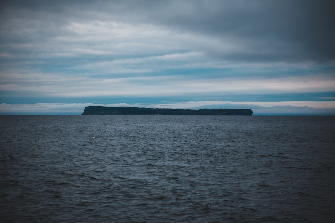 black rock formation on sea under white clouds during daytime