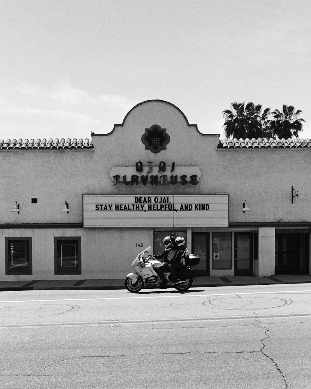 grayscale photo of man riding motorcycle in front of UNKs building