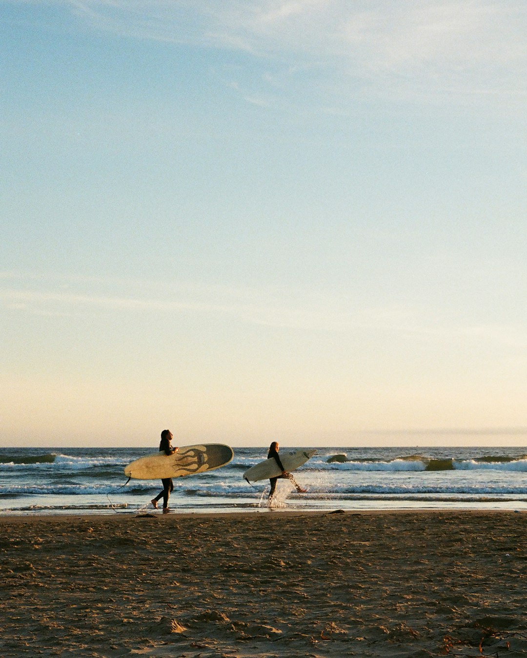 2 people walking on beach during daytime