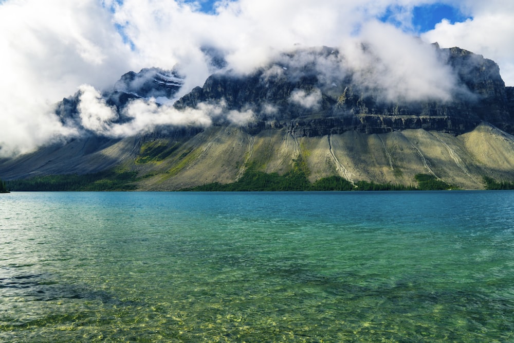 green and gray mountain beside body of water