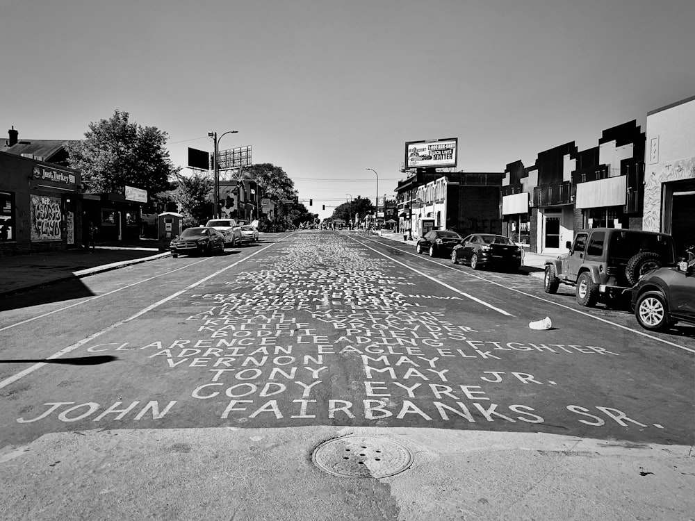 Foto en escala de grises de la calle de la ciudad con coches aparcados en el lateral