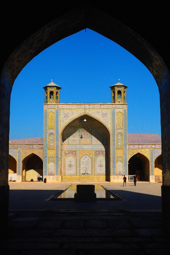 people walking on gray concrete pathway near green and brown concrete building during daytime in Nasir al-Mulk Mosque Iran