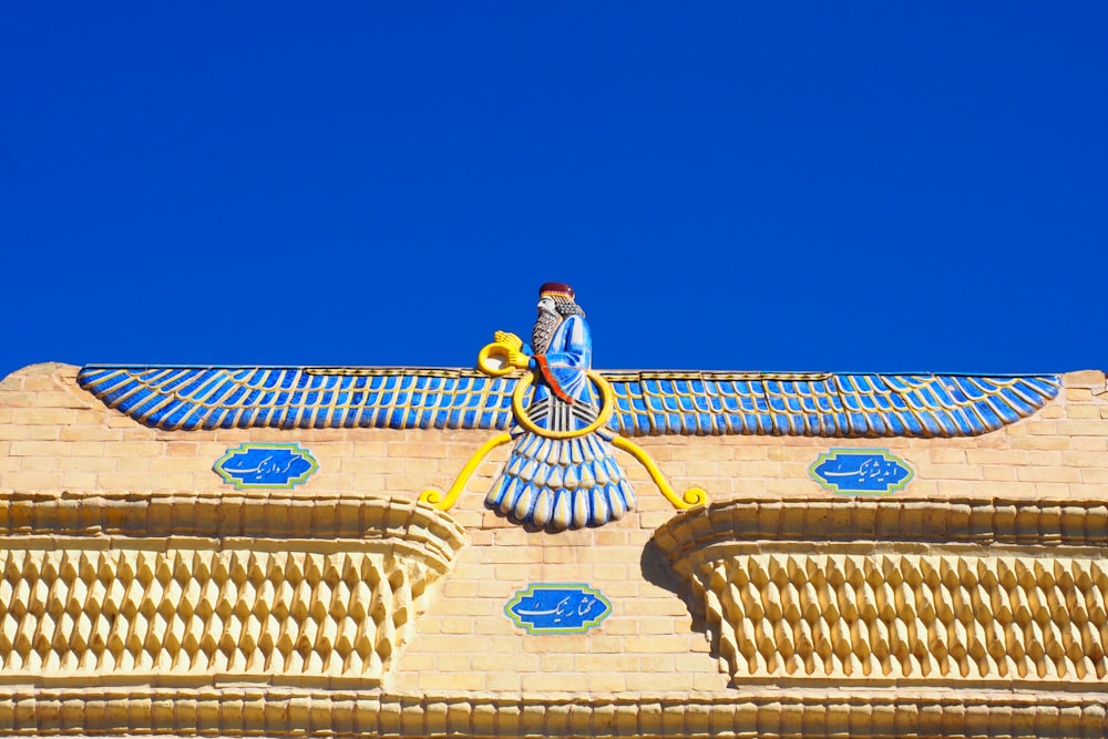 blue and yellow bird on brown concrete building under blue sky during daytime