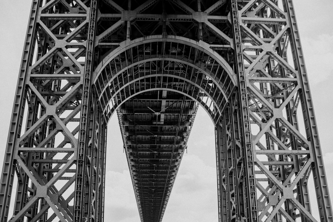 grayscale photo of bridge under cloudy sky