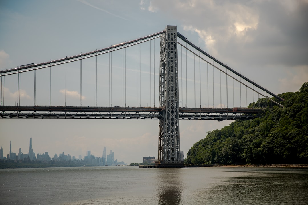 gray bridge over river under blue sky during daytime