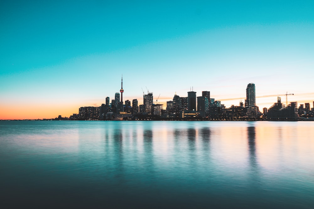 city skyline across body of water during night time