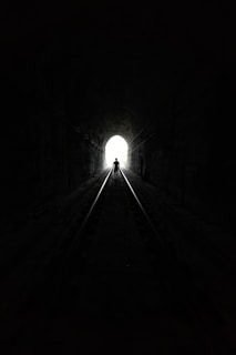 grayscale photo of tunnel with light