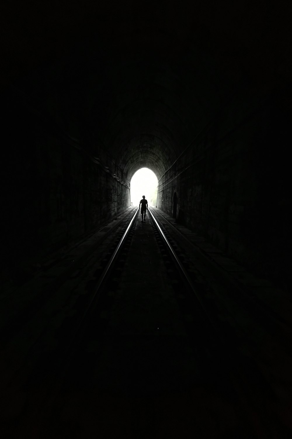 foto in scala di grigi del tunnel con la luce