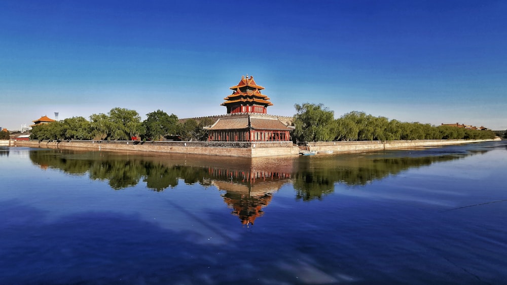 昼間の青空の下、湖畔の茶色と緑の寺院