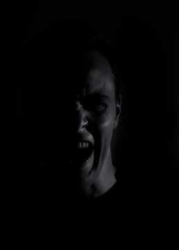 Close-up of a character's face showing intense emotion in a dark room.