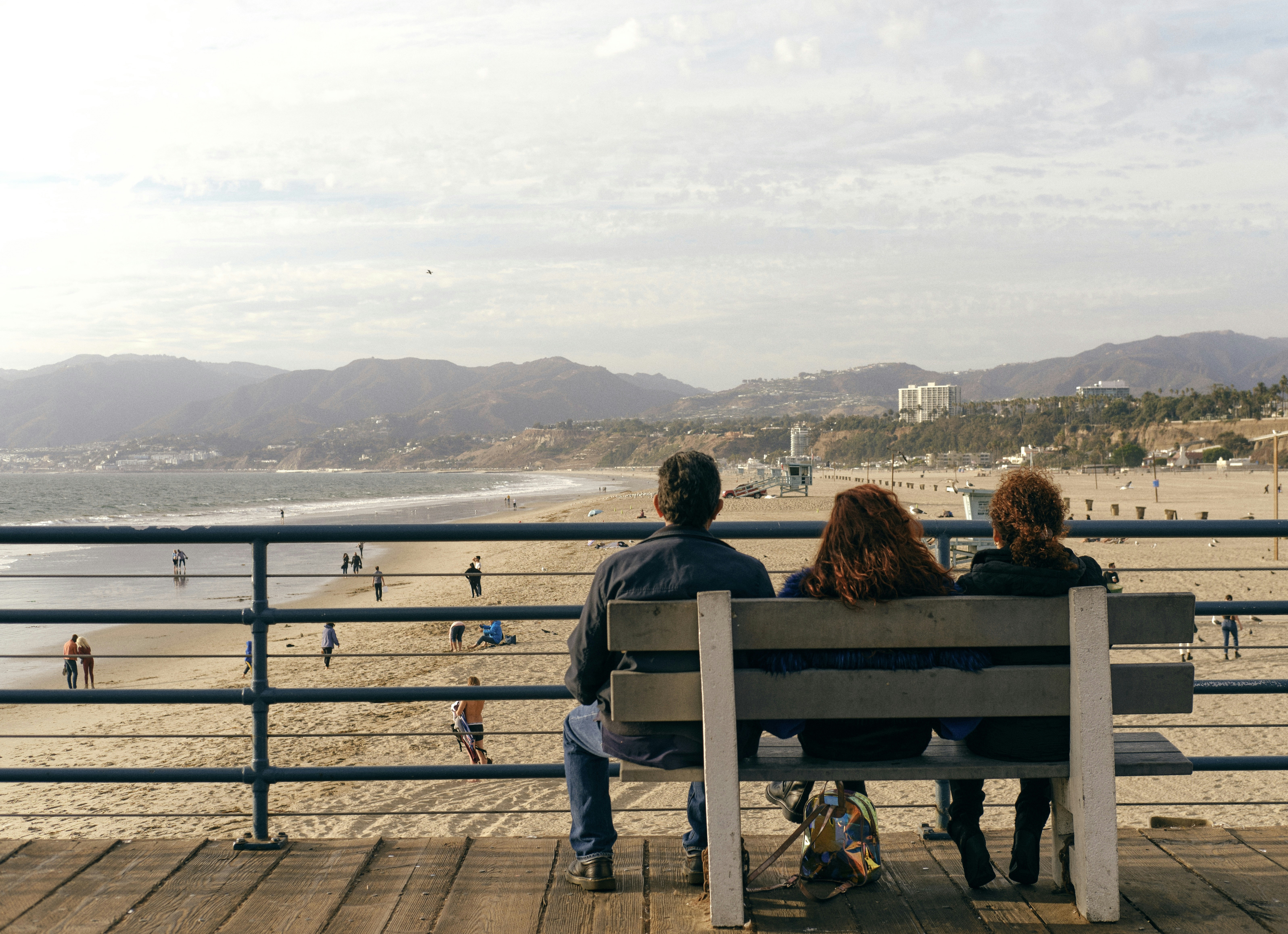 2 women sitting on bench looking at the sea during daytime