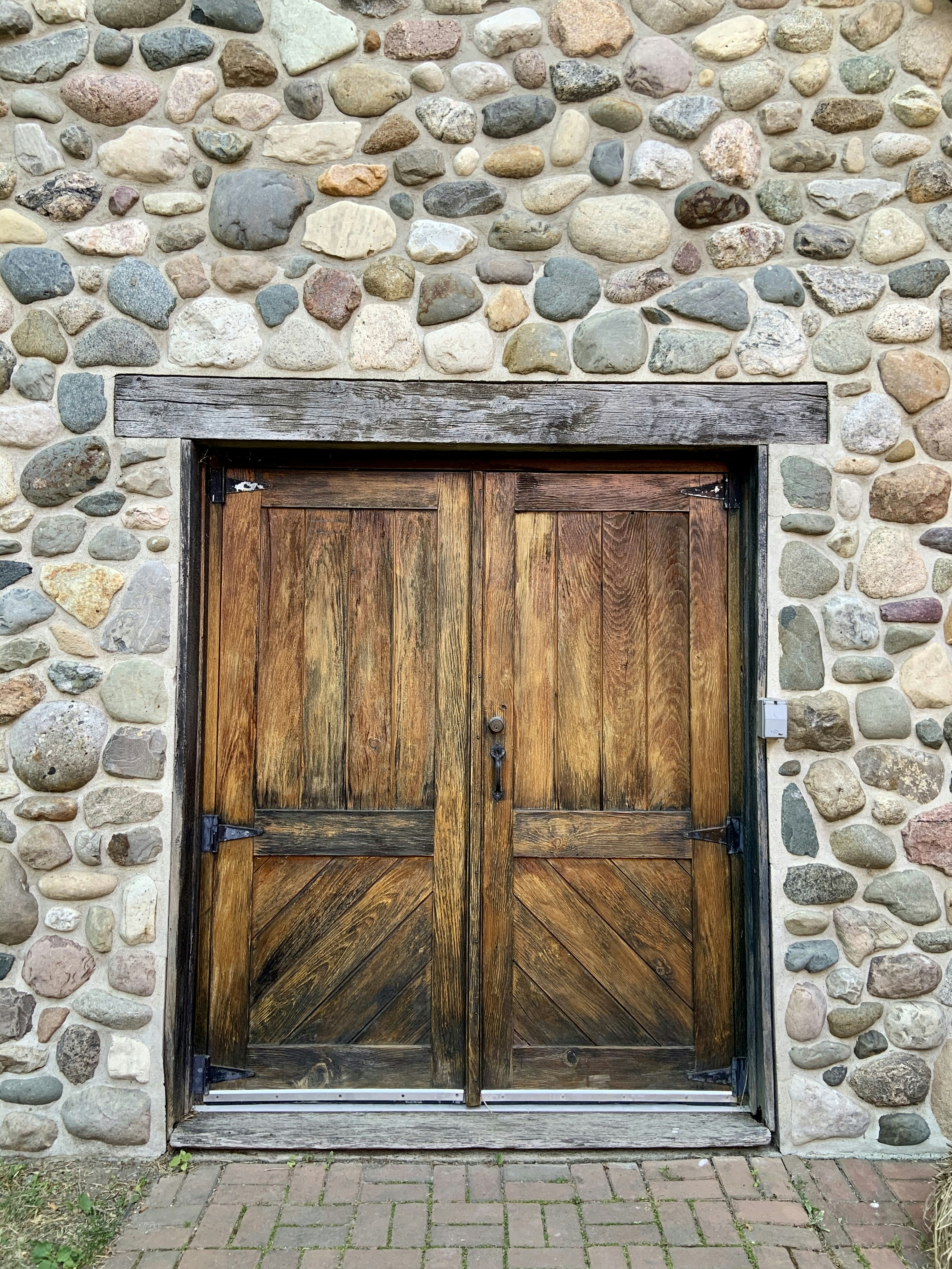 Detail of rustic wooden door with iron hinges, surrounded by natural stone walls.