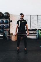man in black crew neck t-shirt and black shorts carrying barbell