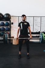 man in black crew neck t-shirt and black shorts carrying barbell