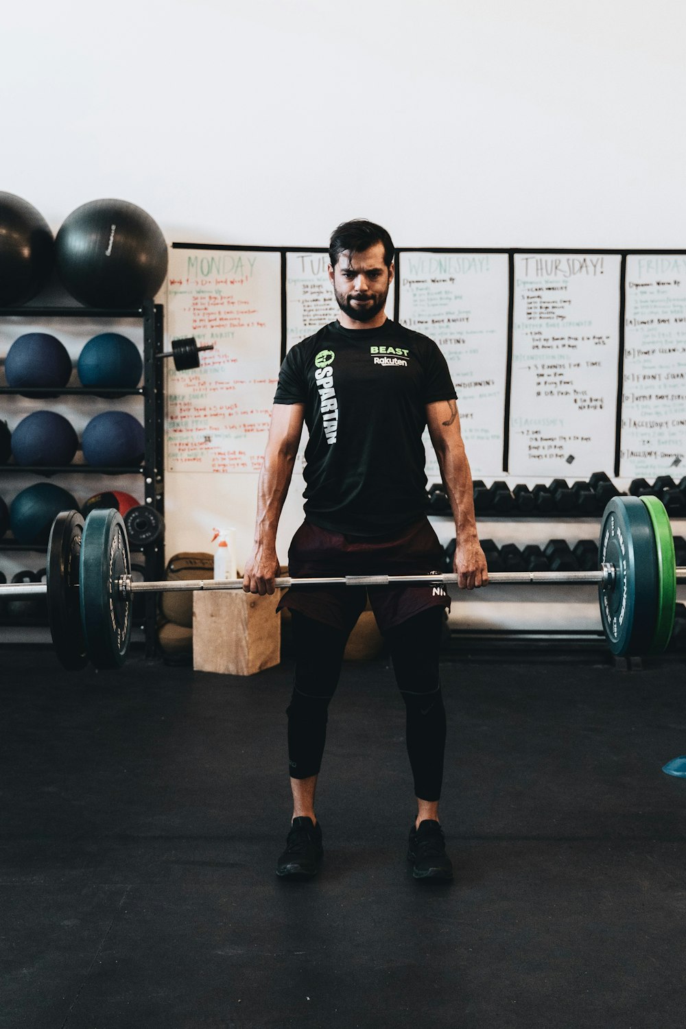 Hombre con camiseta negra de cuello redondo y pantalones cortos negros con barra