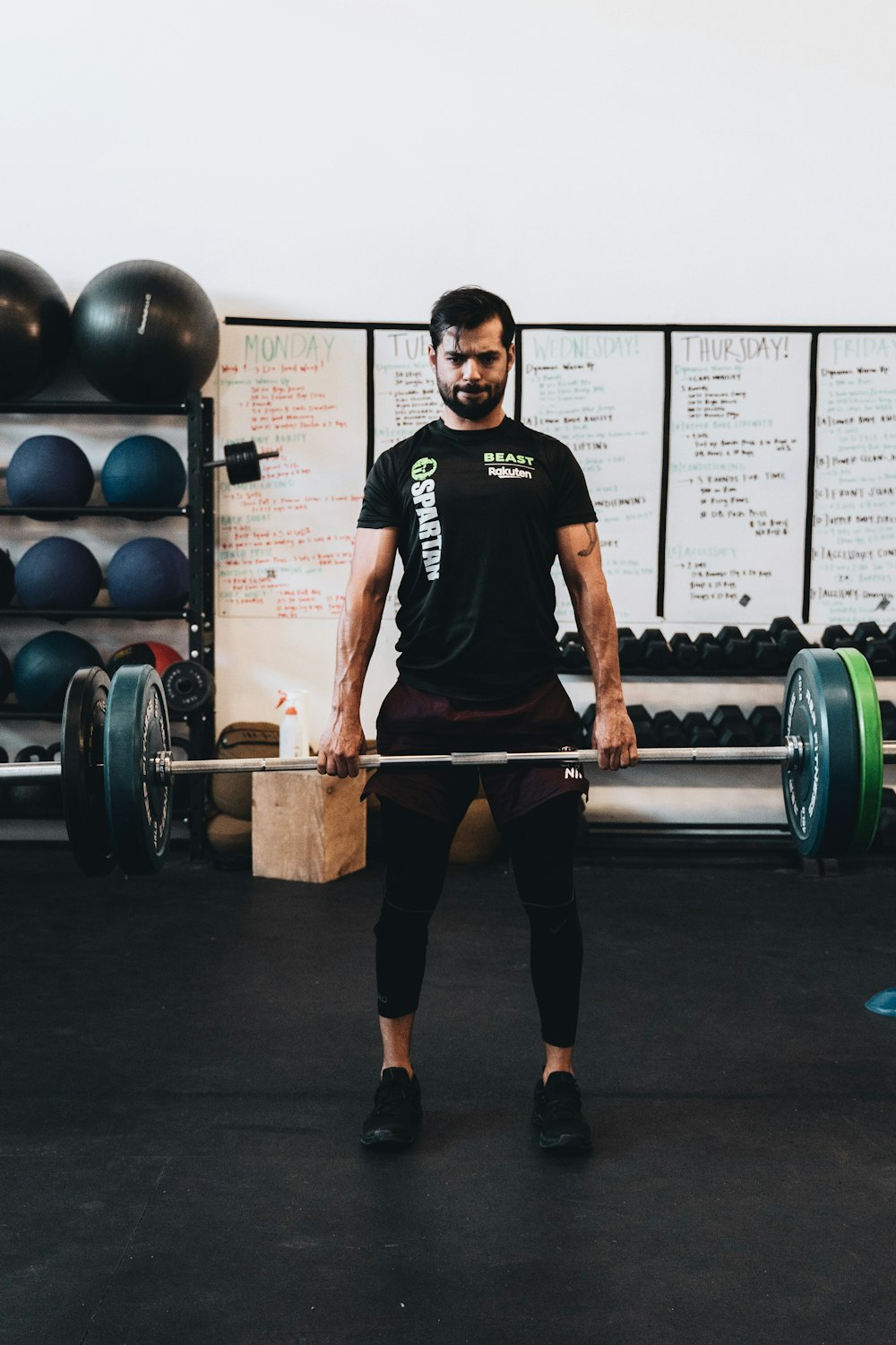 man in black crew neck t-shirt and black shorts carrying barbell