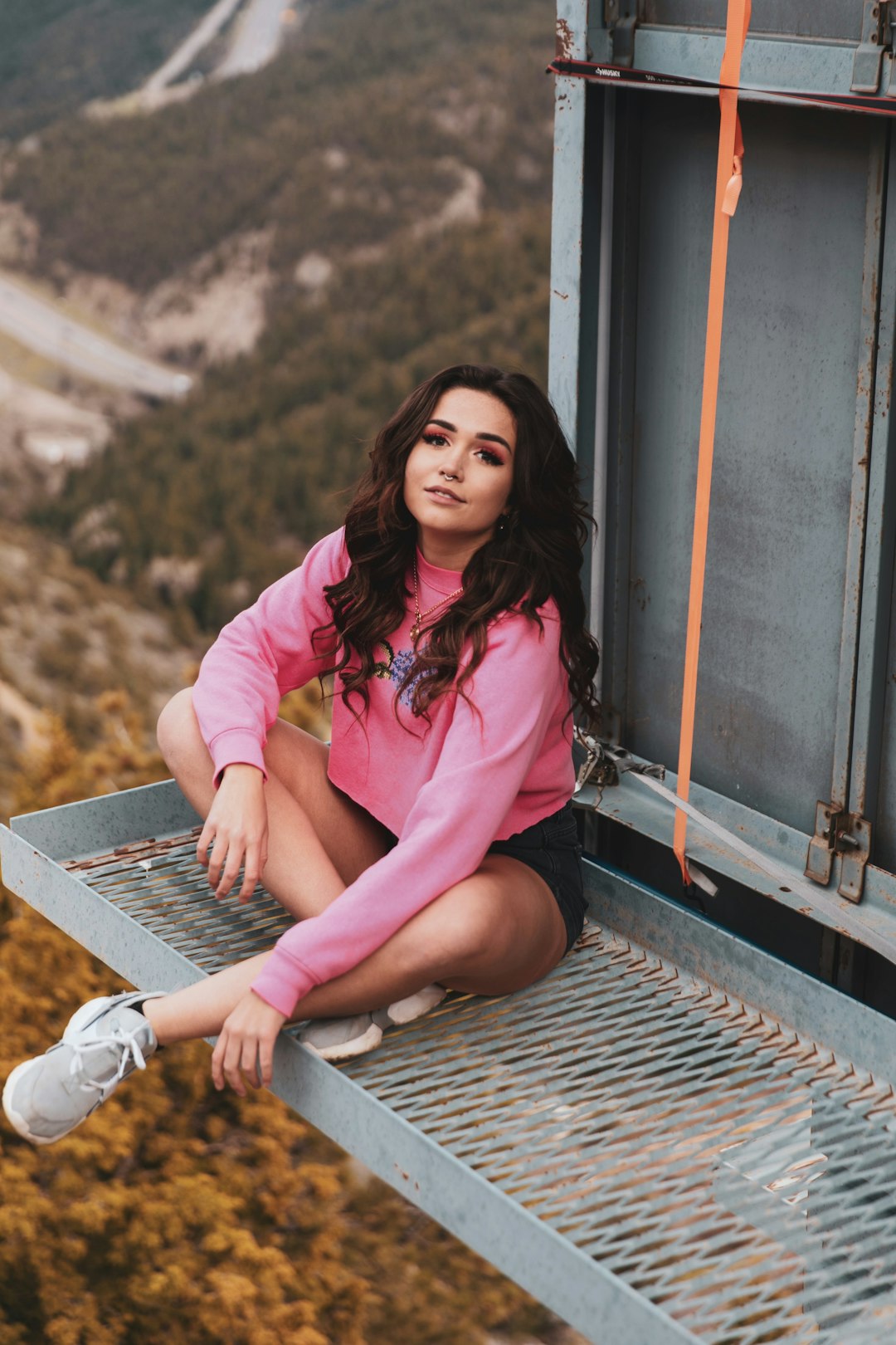 woman in pink jacket sitting on train rail during daytime