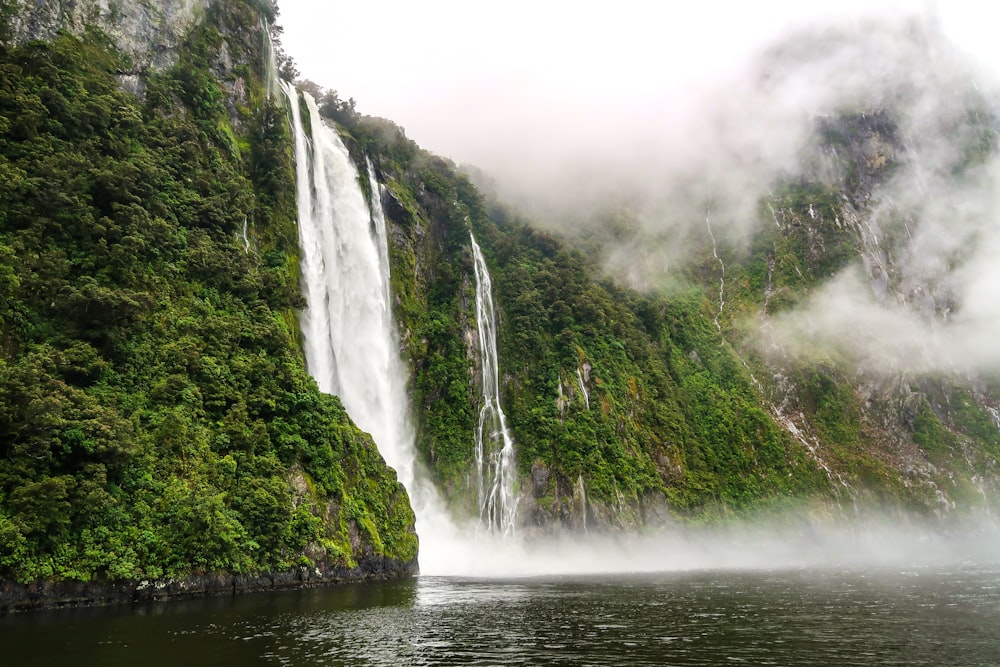 waterfalls on green mountain during daytime