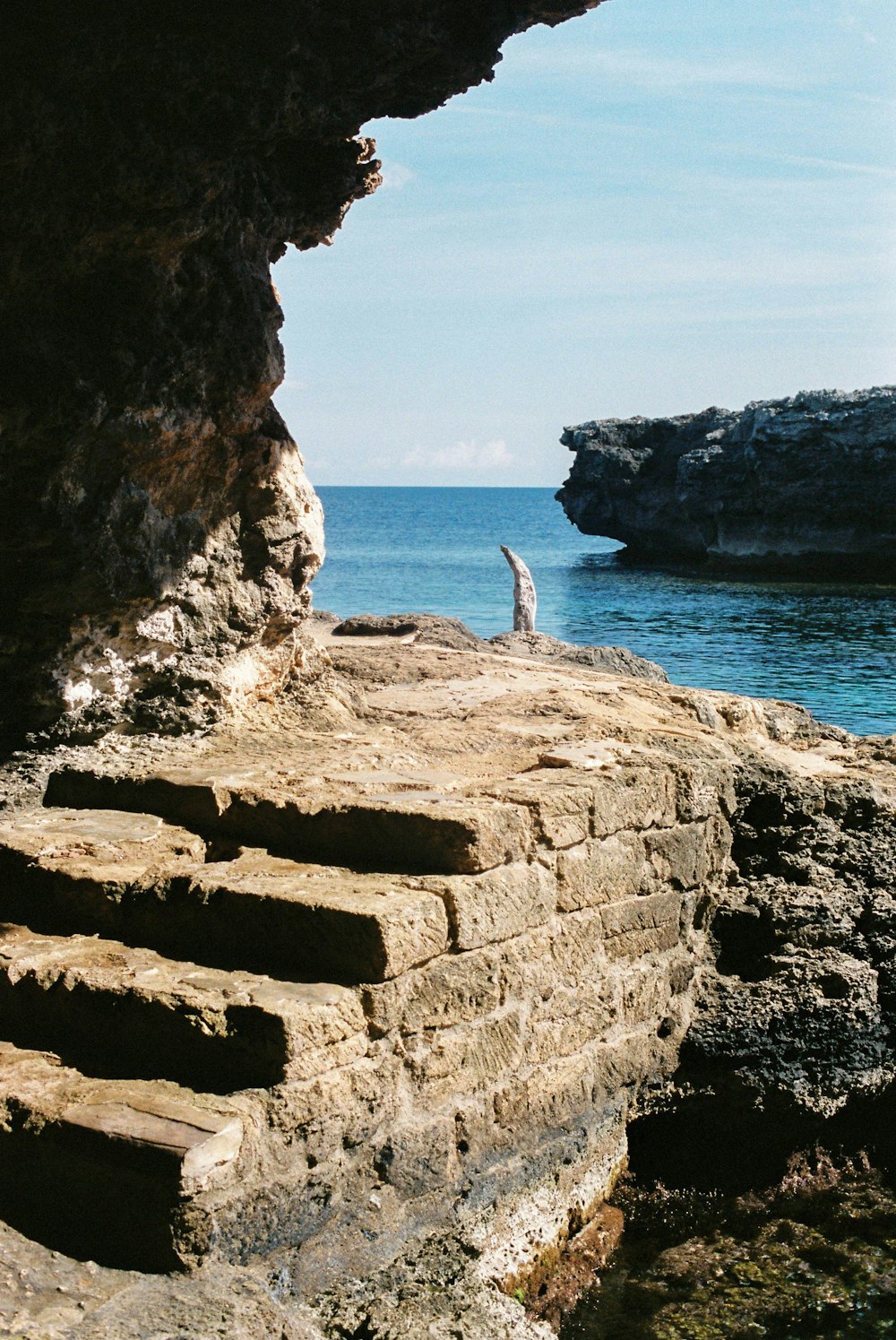 person standing on rock formation near sea during daytime