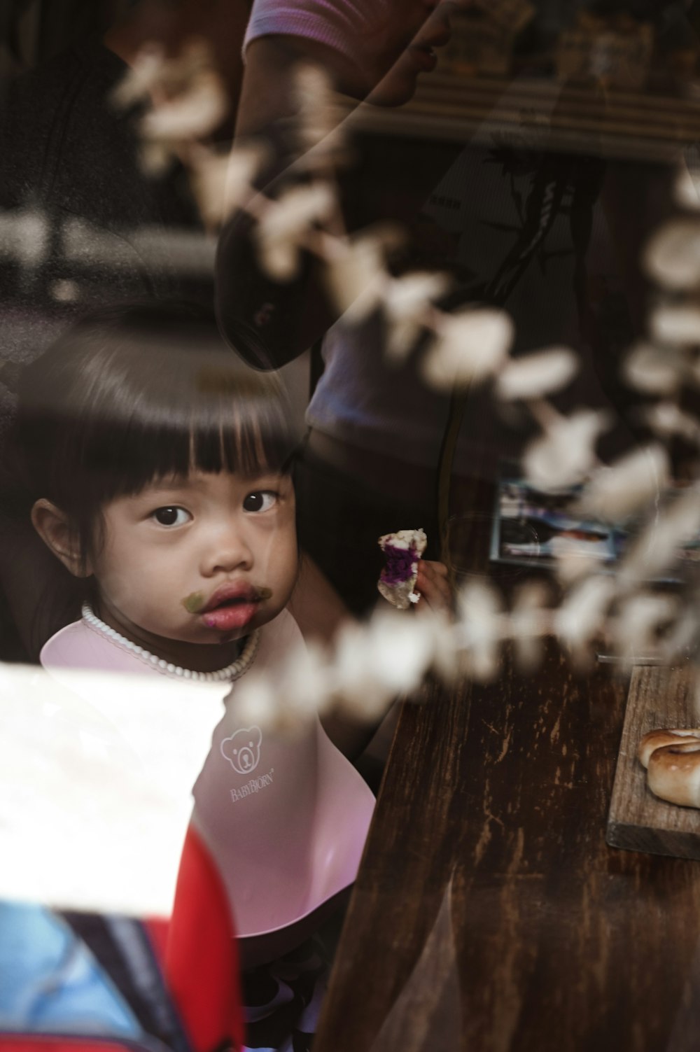 girl in pink and white shirt standing beside brown wooden table