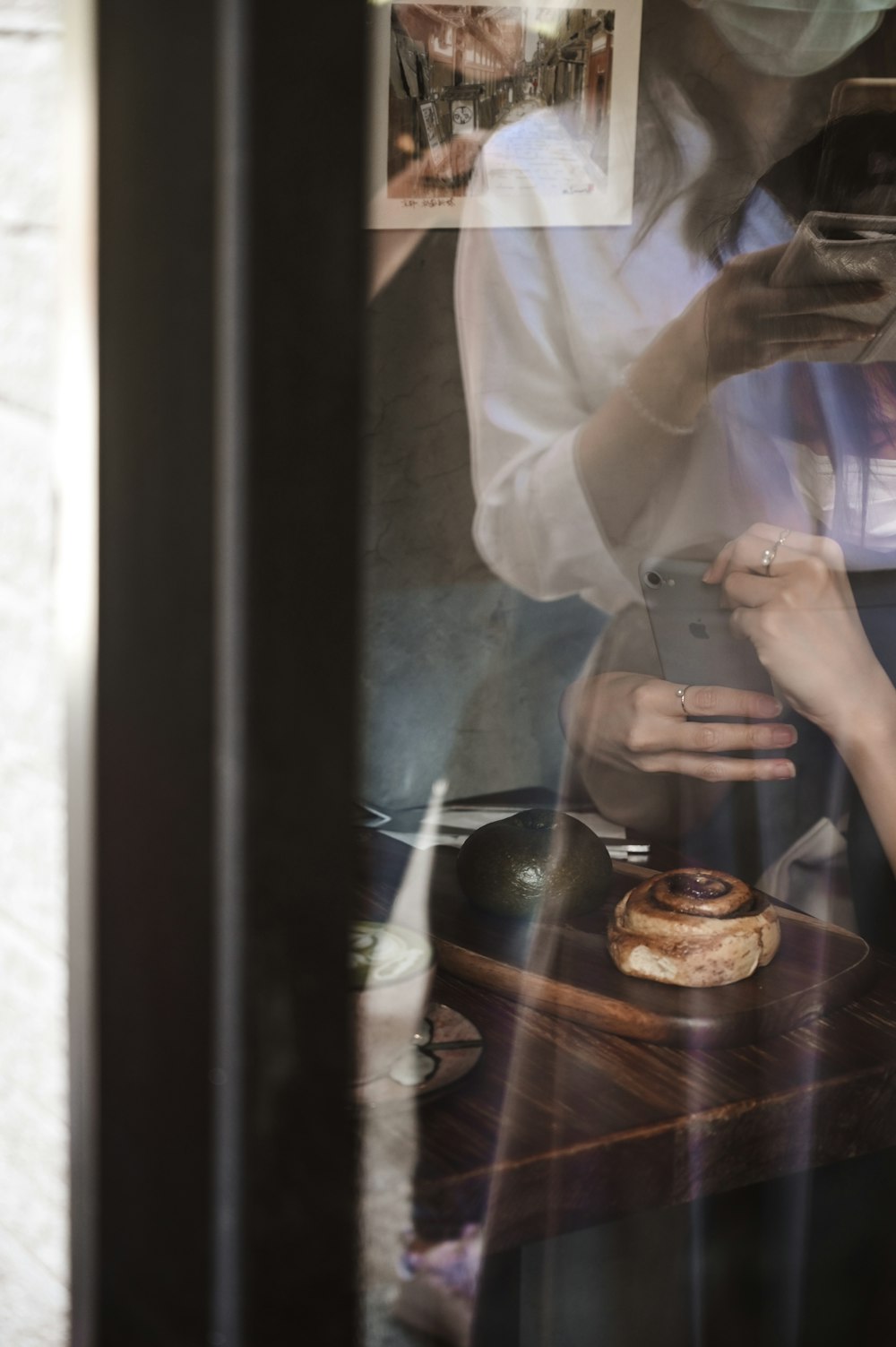 person in white long sleeve shirt holding brown pastry