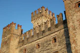 The ancient stone walls of the Castello Angioino-Aragonese under a bright sky.