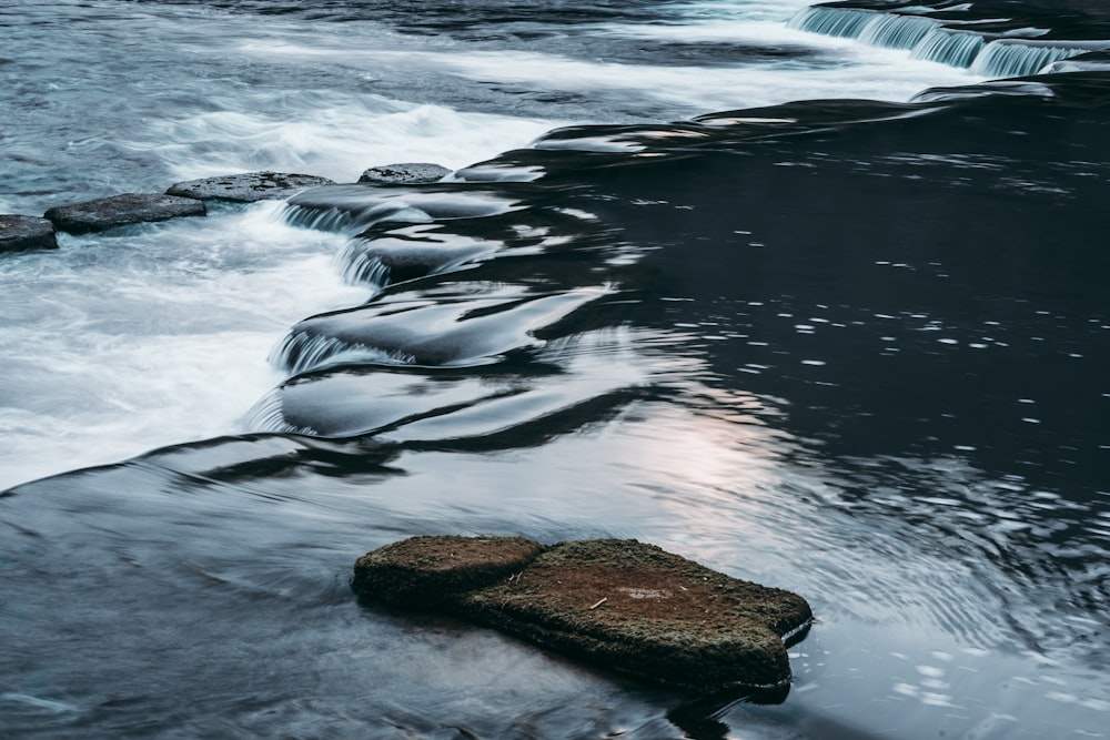 Le onde d'acqua colpiscono le rocce durante il giorno