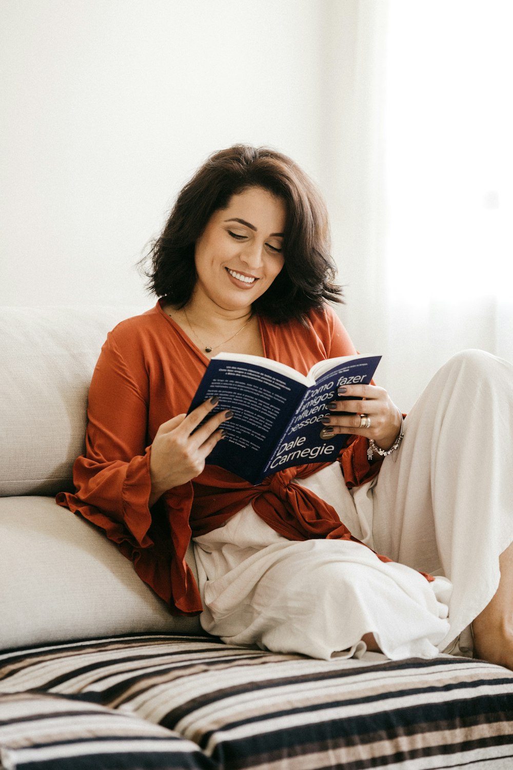 Femme en chemise à manches longues orange tenant un livre bleu