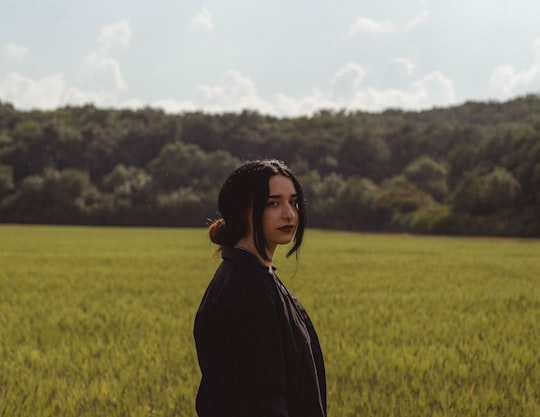 woman in black jacket standing on green grass field during daytime in Kerecsend Hungary