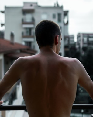 topless man standing on sidewalk during daytime
