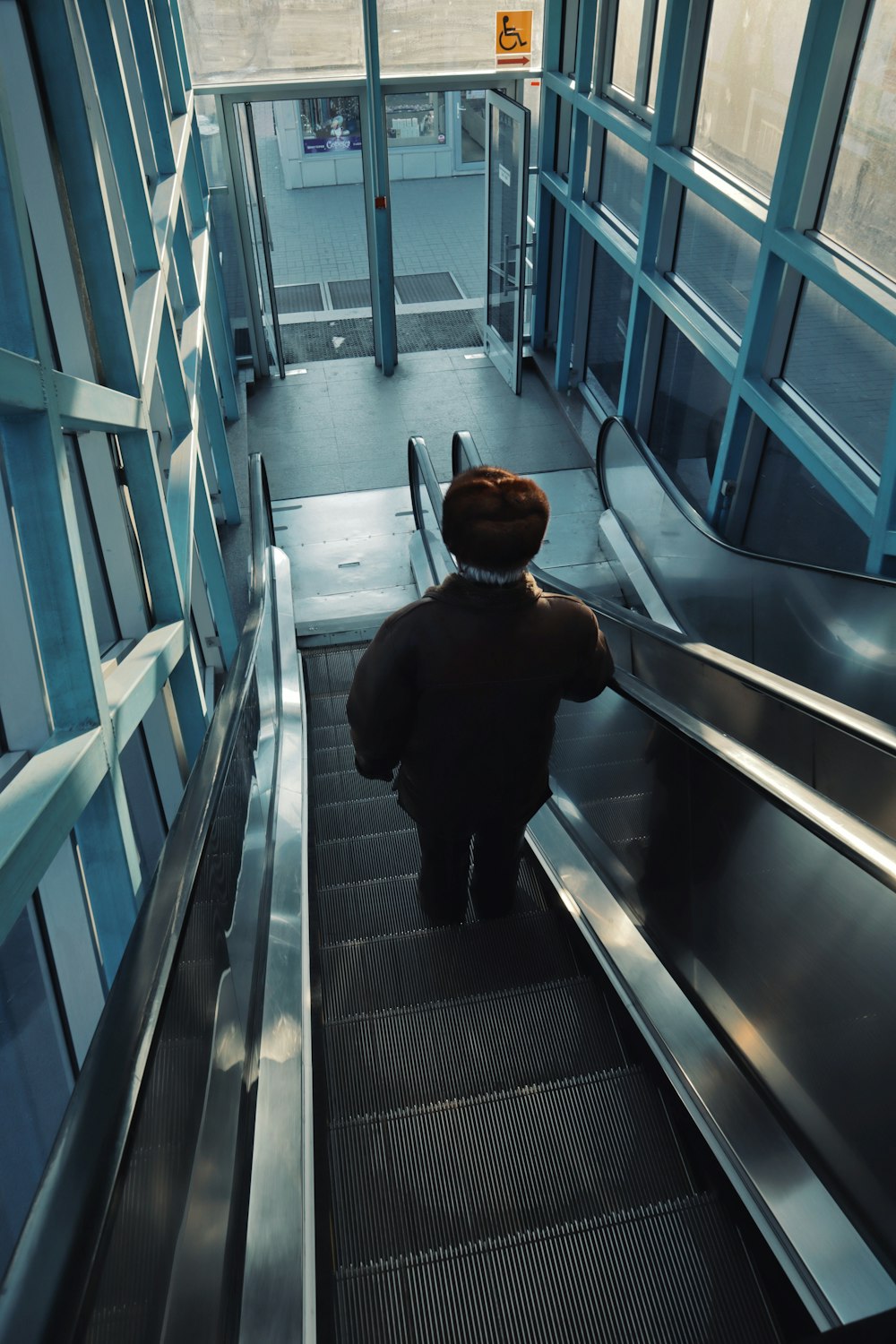 man in black jacket walking on escalator