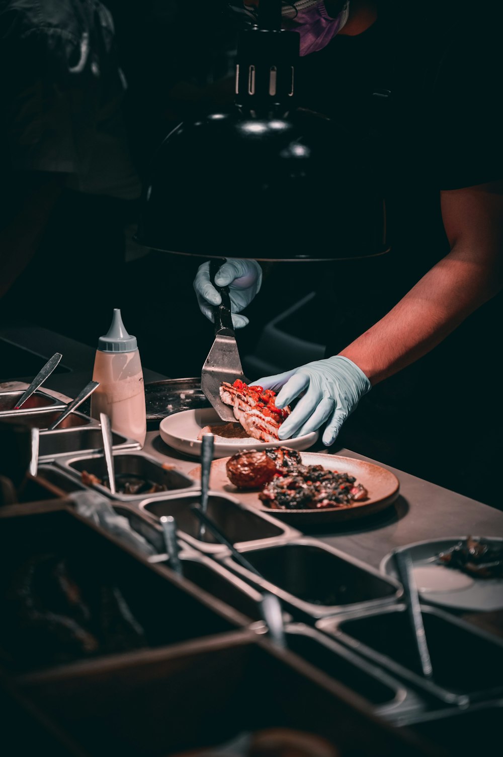 person holding stainless steel fork and knife slicing meat on brown wooden table